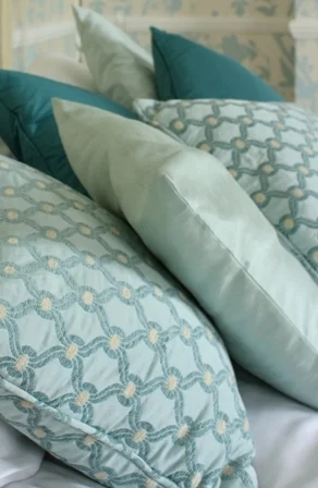 A layered arrangement of pale aqua cushions with geometric and plain fabrics