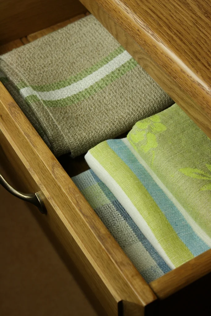 Folded green, blue and natural fabric samples arranged inside an oak drawer