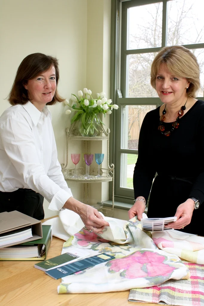 Dorinda Follis and Mary-Louisa Glynn comparing fabric samples at a design table