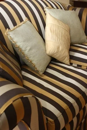 Cream and brown striped armchair layered with pale green fringed cushions